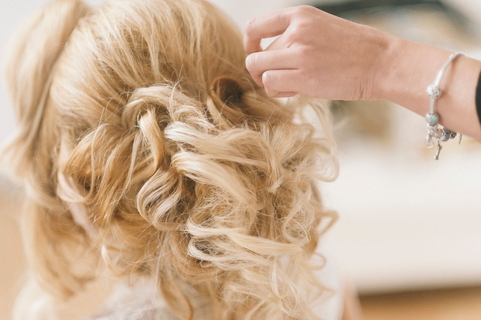 A blonde updo with soft curls being pinned in place