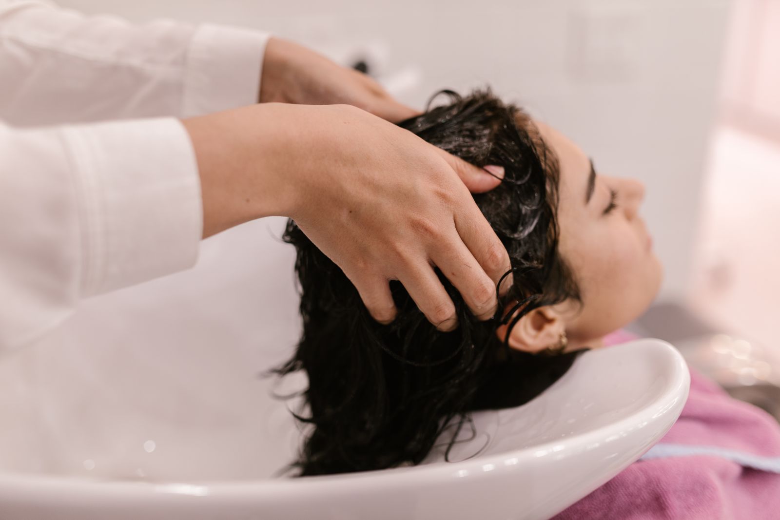 A stylist massaging a client’s scalp at the shampoo bowl